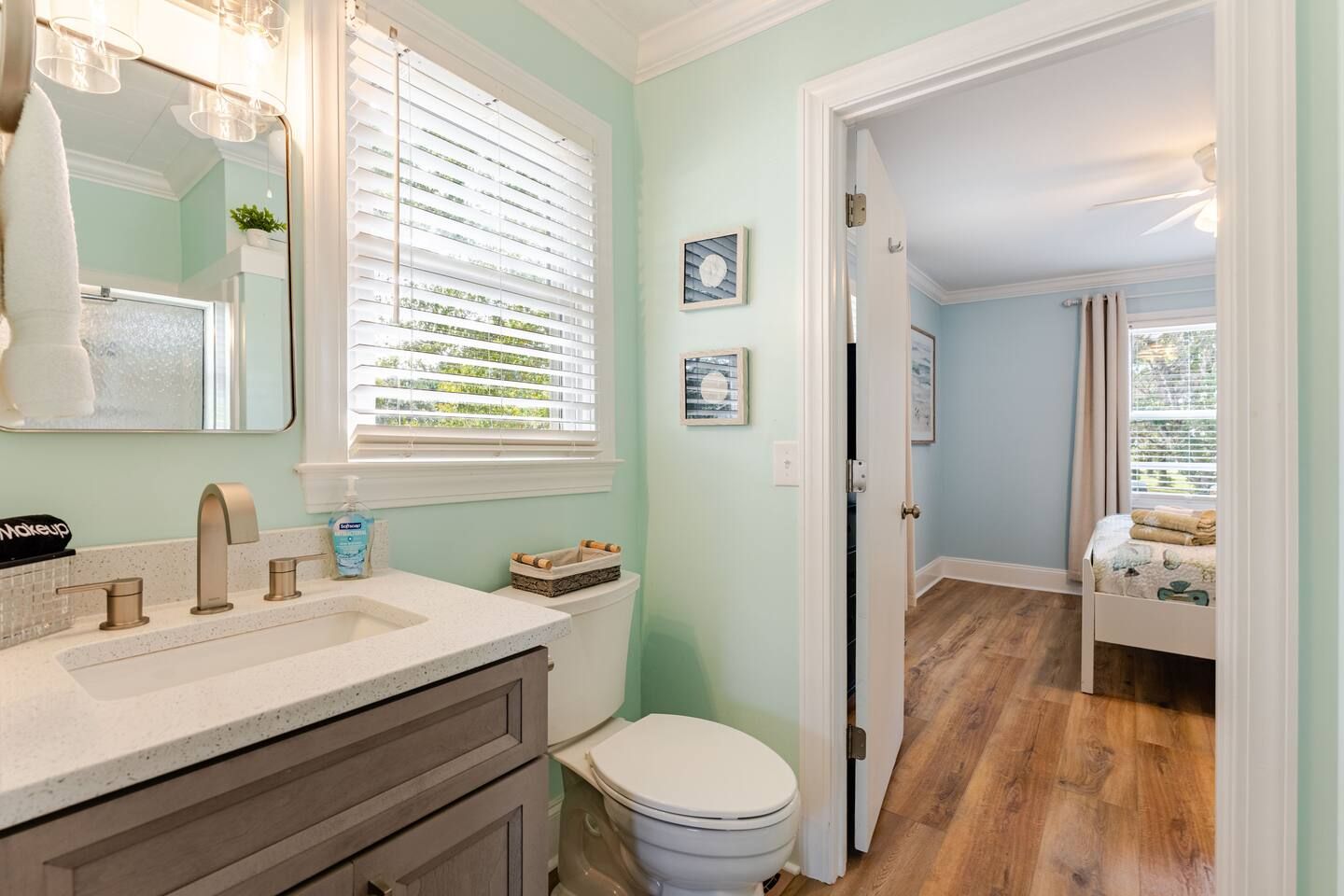 A bathroom with a white sink, a toilet, and a window with blinds.