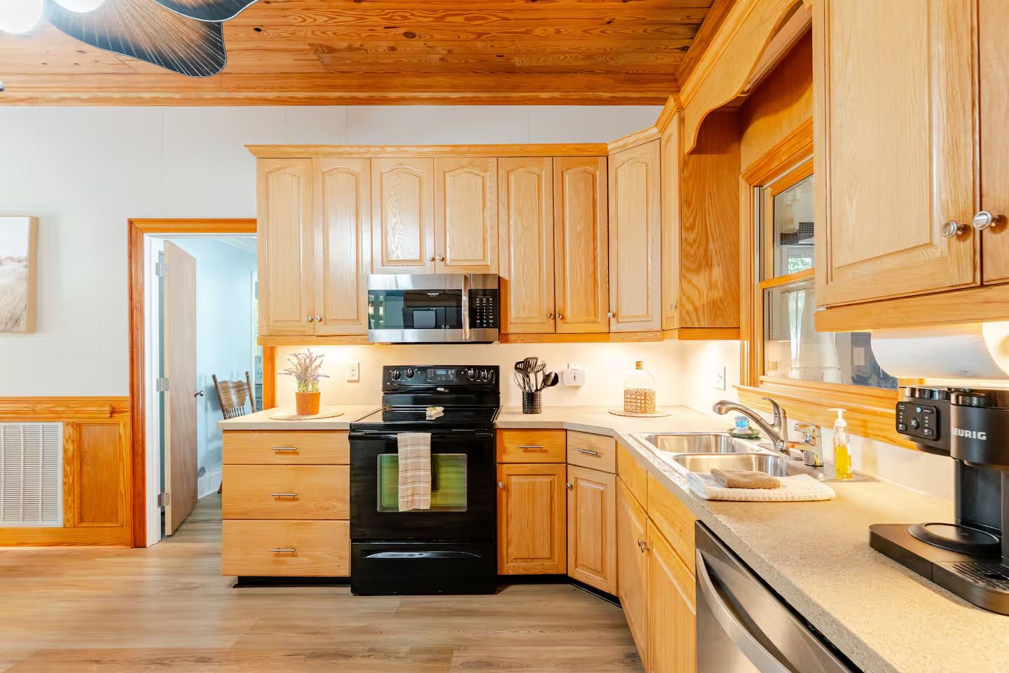 Eine moderne Küche mit Holzausbau, einer Edelstahl-Mikrowelle und einem schwarzen Backofen.