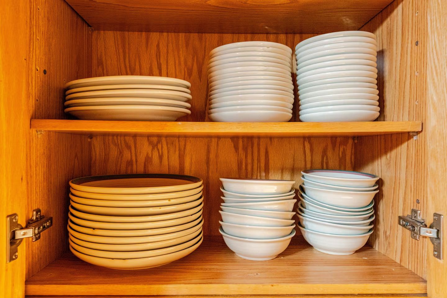 A wooden cabinet with multiple shelves holding stacks of plates.