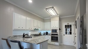 A modern kitchen with white cabinets, a granite countertop, and a built-in island with bar stools. - Abbeys at  WestLake , Wonderful 3-bedroom house with AC in charming Martinez. (Martinez)