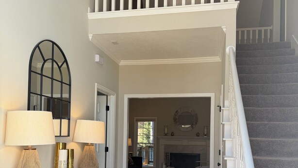 A spacious living area with a staircase, a console table with lamps, a patterned rug, and a view into the dining area. - Abbeys at  WestLake , Wonderful 3-bedroom house with AC in charming Martinez. (Martinez)