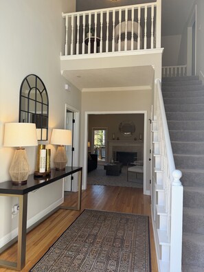 A spacious living area with a staircase, a console table with lamps, a patterned rug, and a view into the dining area. - Abbeys at  WestLake , Wonderful 3-bedroom house with AC in charming Martinez. (Martinez)