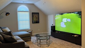A cozy living room with a ceiling fan, a large flat-screen TV, a glass coffee table, a gray sofa, and a window with blinds. - Abbeys at  WestLake , Wonderful 3-bedroom house with AC in charming Martinez. (Martinez)