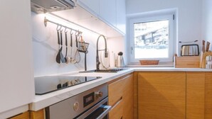 Eine moderne Küche mit weißen Schränken, Holzelementen und einem Fenster mit Blick nach draußen.