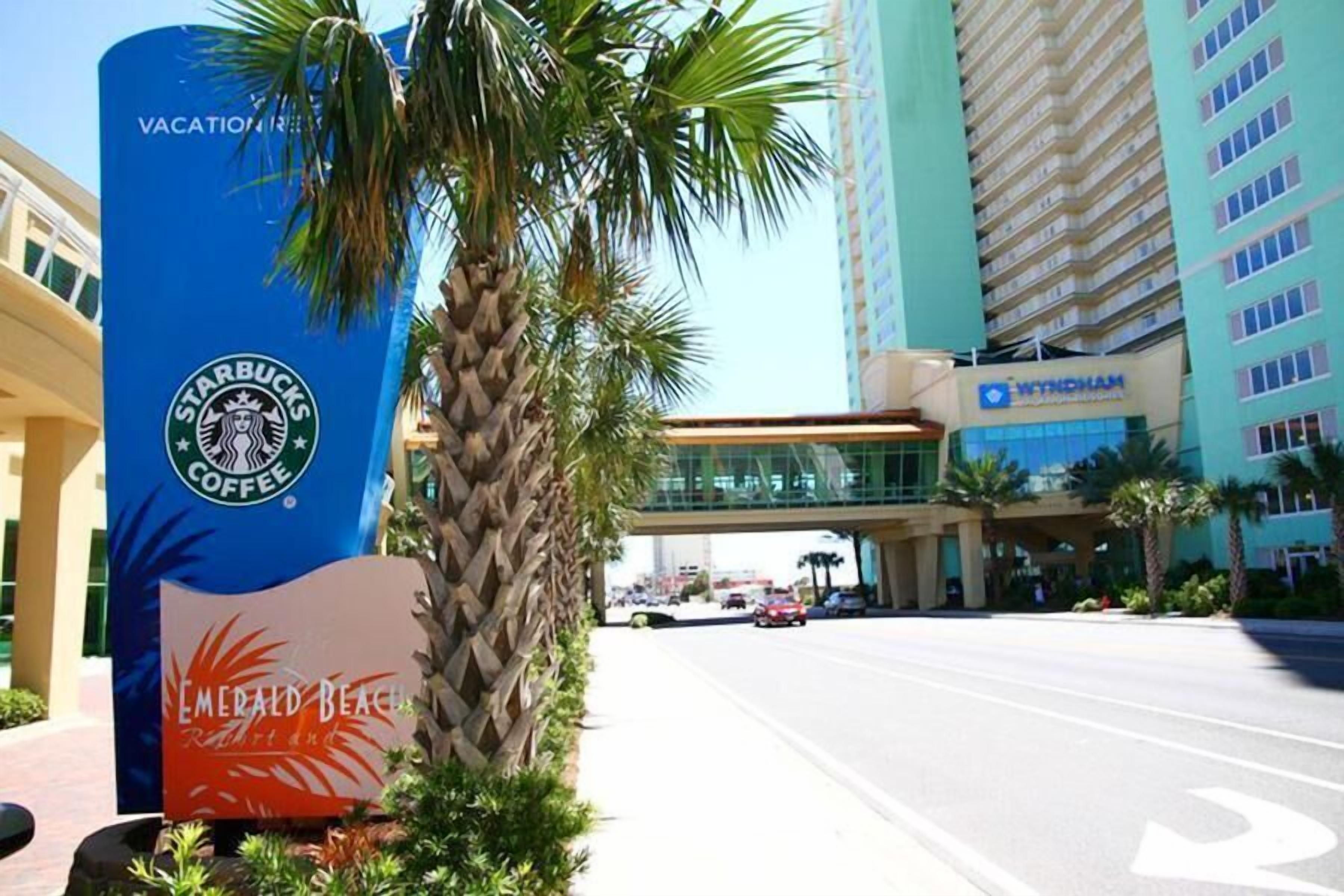 A Starbucks Coffee sign with a palm tree and a sign for Emerald Beach Resort.