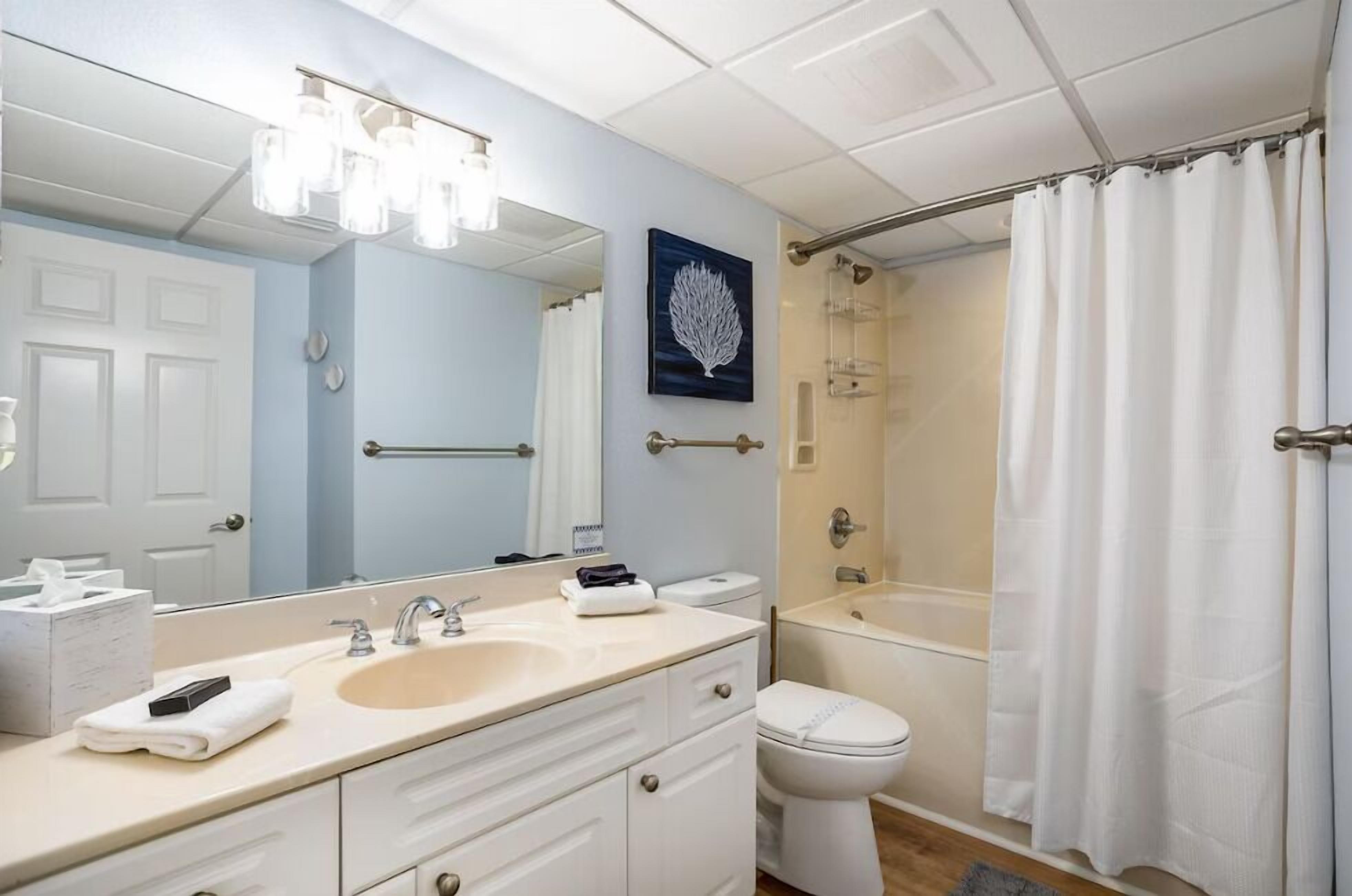 Un baño con lavamanos, espejo, inodoro y ducha.