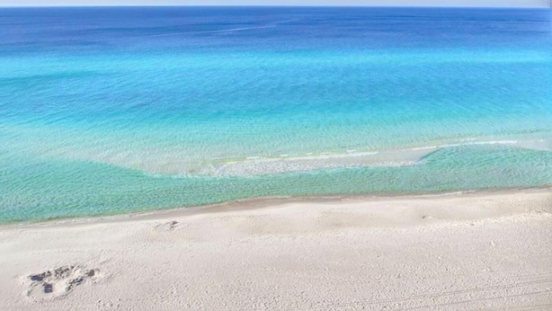 Een strand met helder turquoise water en een zandstrand.