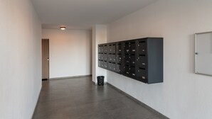 A hallway with lockers, a trash bin, and a door at the end.