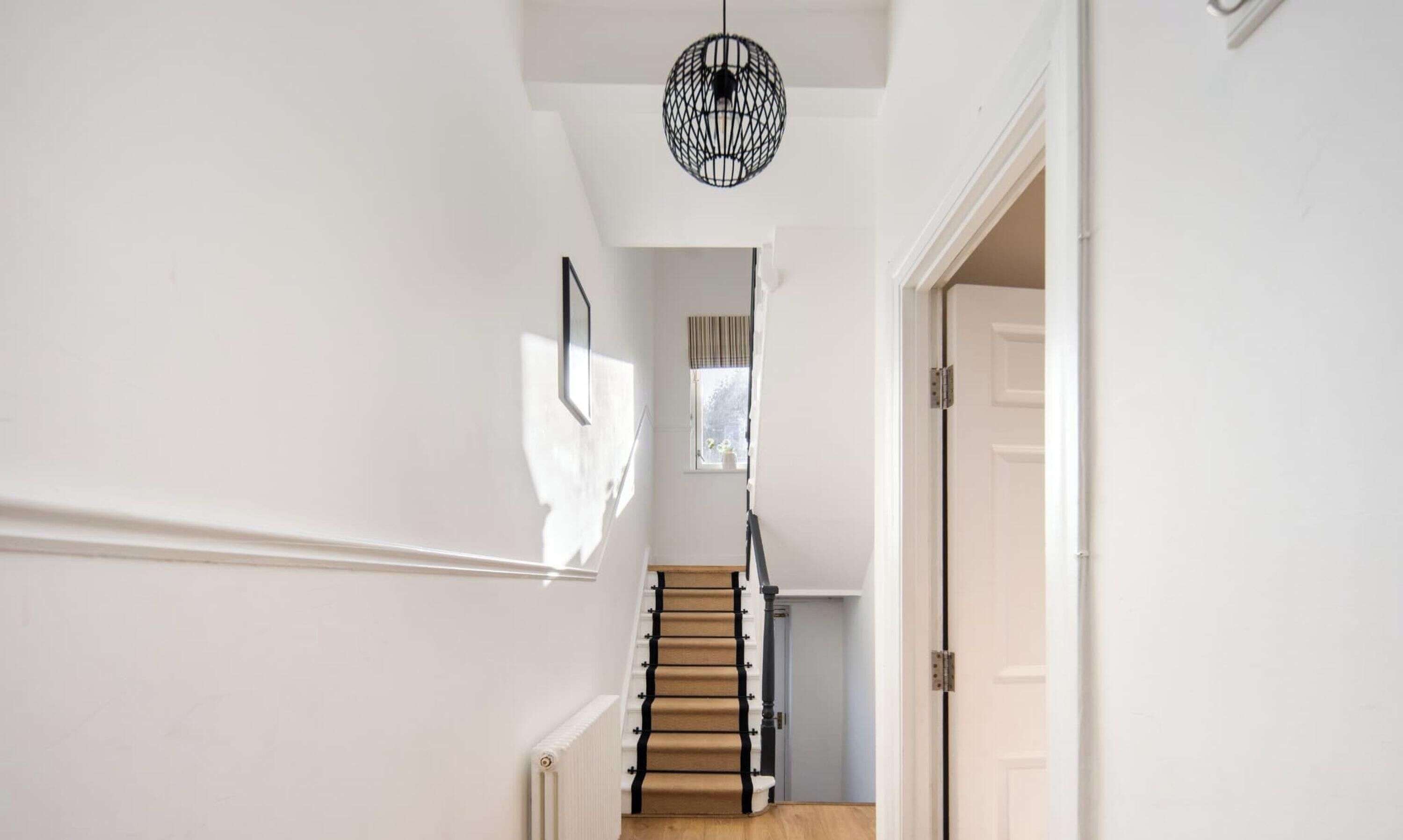 A staircase with a wooden handrail and a black metal light fixture above it.