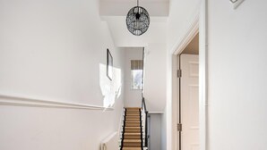 A staircase with a wooden handrail and a black metal light fixture above it. - 10 Mins Walk to The Oval The Kennington Retreat (London)