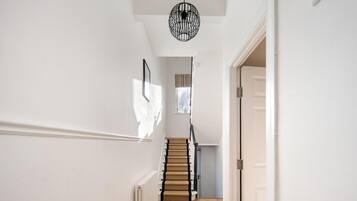 A staircase with a wooden handrail and a black metal light fixture above it.