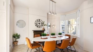 A dining room with a round table, orange chairs, and a fireplace. - 10 Mins Walk to The Oval The Kennington Retreat (London)