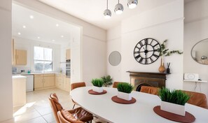 A modern kitchen with white cabinets, a large window, and a dining area with a white table and brown chairs. - 10 Mins Walk to The Oval The Kennington Retreat (London)