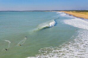 Uma praia com água cristalina, ondas e areal.