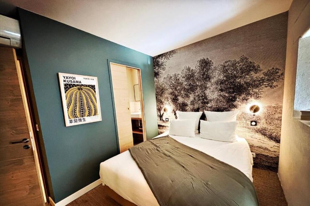 Ein Schlafzimmer mit einem Bett, einem Poster an der Wand und einem Wandgemälde mit Bäumen.
