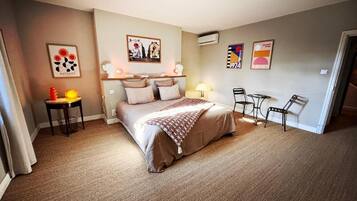 Ein Schlafzimmer mit einem Bett, Nachttischen, einem Sessel und Wandbildern.