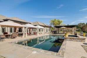 A swimming pool with lounge chairs and umbrellas, surrounded by stone tiles and a pergola. - Pool, Peacocks & Views! Lavish Retreat in Gilroy (Gilroy)