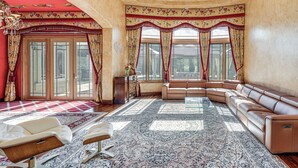 Ein geräumiges Wohnzimmer mit einer großen Eckcouch, einem Glastisch und einem gemusterten Teppich.