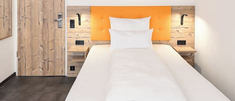 A single bed with a wooden headboard, a bedside table, and a nightstand.