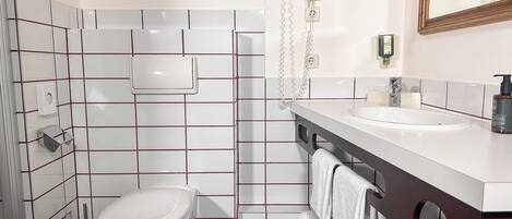 A bathroom with a toilet, sink, and hairdryer on the wall.