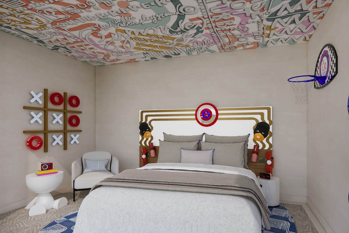 A bedroom with a bed, a bedside table, a chair, a wall decoration, and a ceiling with a colorful pattern.