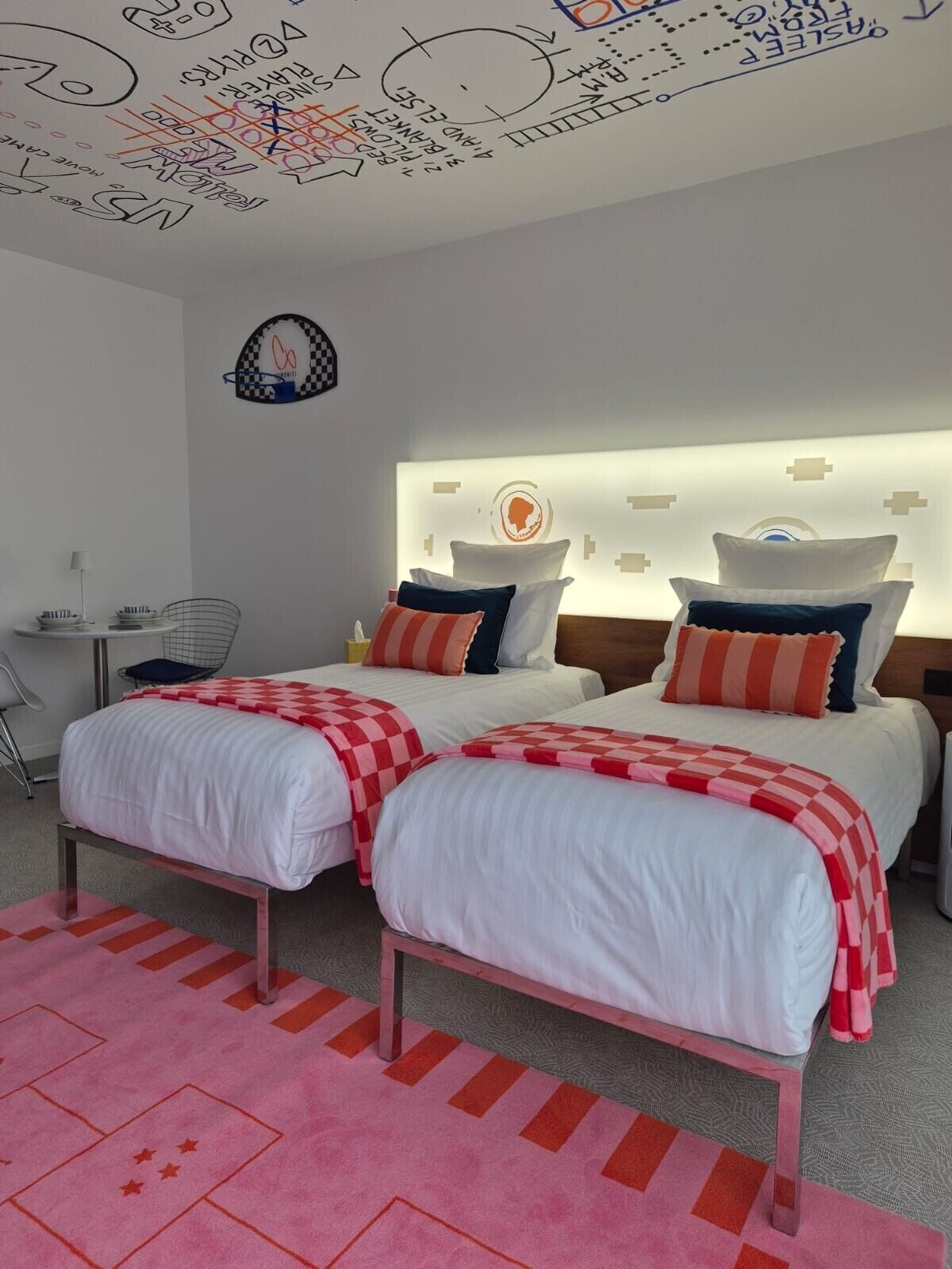A hotel room with two beds, a desk, and a chair.