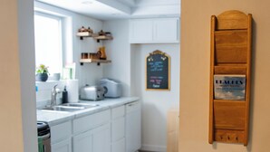 Een keuken met witte kastjes, een krijtbordmenu en een houten bord aan de muur.