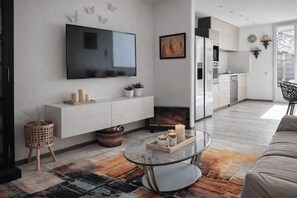 A modern living room with a flat-screen TV, a glass coffee table, and a sofa. - Apartment with Jacuzzi and Courtyard in Andernos (Andernos-les-Bains)