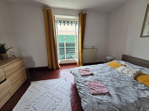 A bedroom with a bed, a dresser, a radiator, and a window with curtains. - 160m² Bright Flat in Central Nîmes (Nîmes)