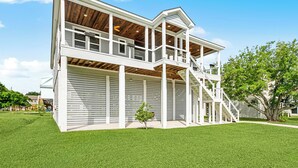Een tweelaags huis met een overdekte veranda en een trap die naar de bovenverdieping leidt.