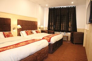 A hotel room with two beds, a sofa, a small table, and a TV.