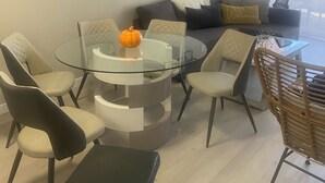 A modern living room with a glass coffee table, comfortable seating, a wall clock, and a decorative wall piece. - Lovely 1-bedroom condo near shops & dining! (Denver)