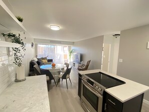 A modern kitchen with a central island, a built-in oven, and a dining area with a round table and chairs. - Lovely 1-bedroom condo near shops & dining! (Denver)