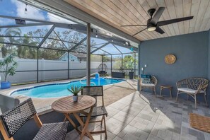Ein überdachter Außenbereich mit Pool, Sitzgelegenheiten und Deckenventilator.