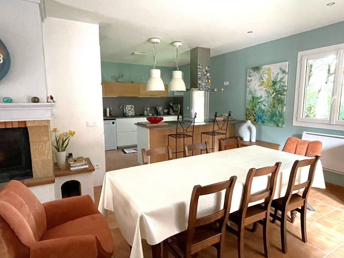A dining area with a table, chairs, and a kitchen in the background.