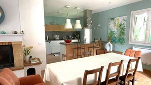 Een eetgedeelte met een tafel, stoelen en een keuken op de achtergrond.