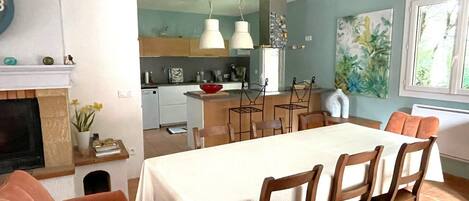 A dining area with a table, chairs, and a kitchen in the background.