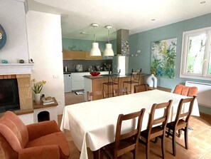 Un espace repas avec une table, des chaises et une cuisine en arrière-plan.
