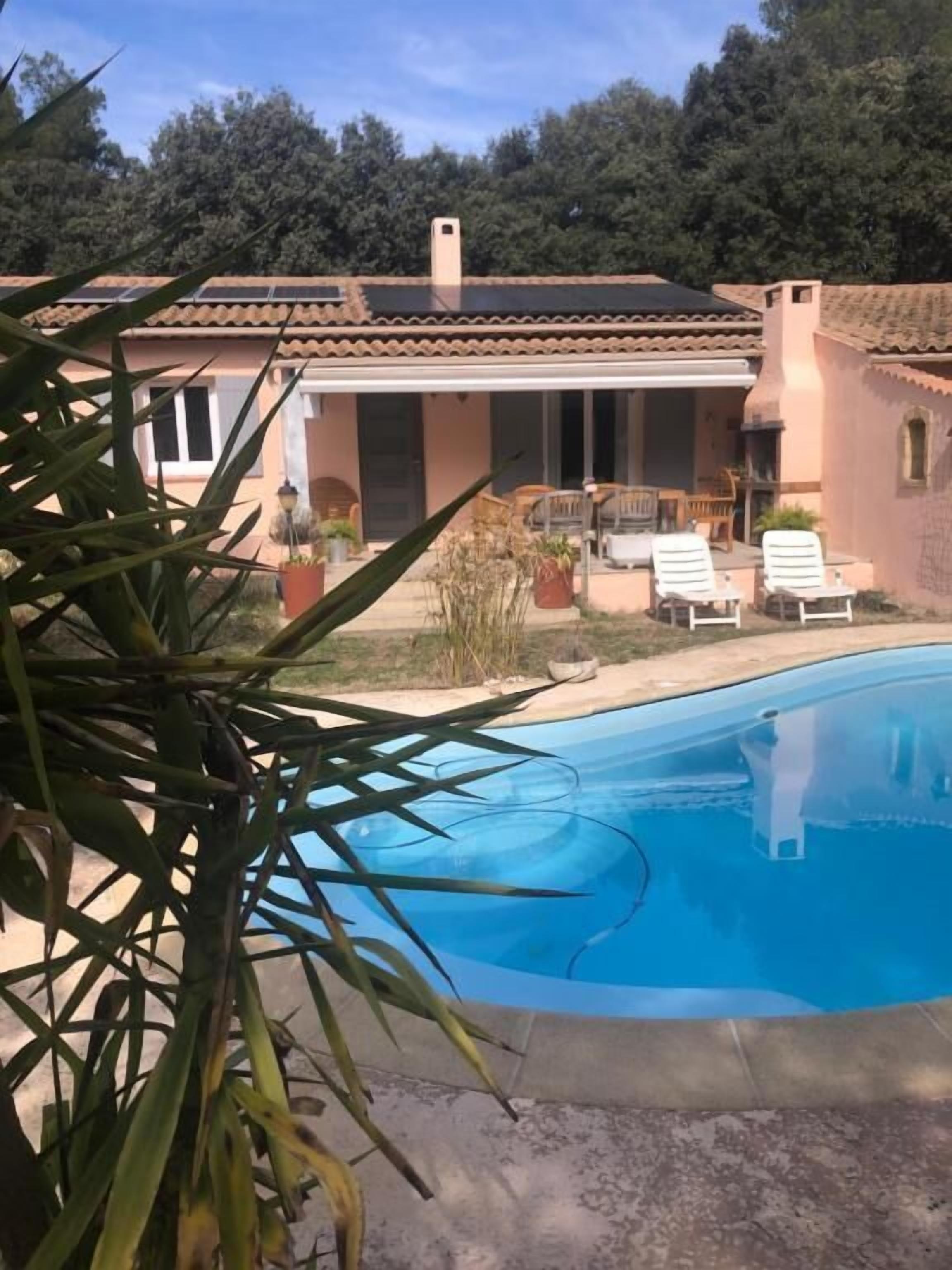 A house with a swimming pool, a patio with chairs, and a garden.
