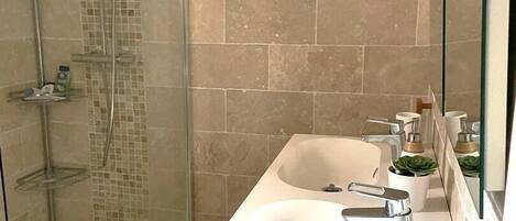 A modern bathroom with a glass shower enclosure, a white sink with a mirror, and a tiled backsplash.