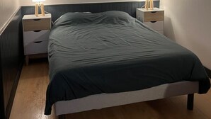 A bedroom with a bed, two bedside tables, and a nightstand with a lamp. - L’Hermione – city center & thermal baths (Rochefort)