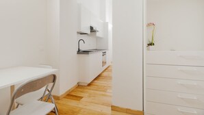 A modern kitchen with white cabinetry, a wooden floor, and a small dining area with a chair. - GuestHost - Modern mezzanine studio apartment of 30 m2, ideal for two people, located on the raised ground floor of a typical Milanese building (stairs to access the apartment).The property is located a stone's throw from the M1 Lima stop in a strategi (Milan)