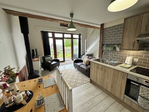Eine moderne Küche mit Holzausstattung, einem eingebauten Backofen und einem großen Fenster mit Blick auf einen Garten.