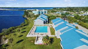 Ein Resort mit großem Pool, mehreren Gebäuden mit blauen Dächern und Blick aufs Wasser.