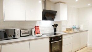 A modern kitchen with white cabinets, a microwave, a toaster, and a dishwasher. - Scandic House Apartments - Long Term Rental Available (Ulverston)