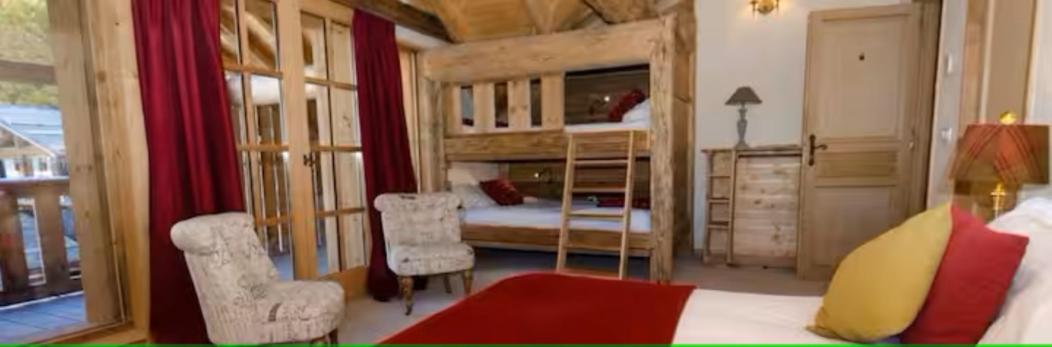 A rustic room with a bunk bed, a wooden dresser, and two armchairs.