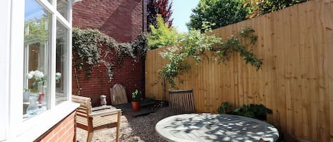 A patio with a round table and chairs, a brick wall, and a wooden fence.