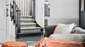 A modern interior with a staircase, a cushioned seating area, and a door with a light switch.