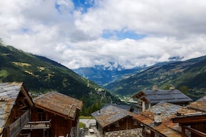 Ein Bergdorf mit traditionellen Holzhäusern und Blick ins Tal.