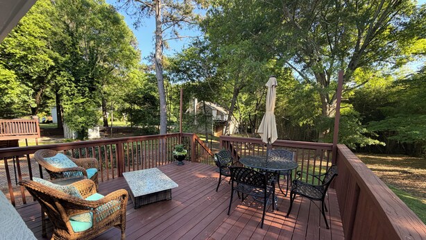 A wooden deck with wicker furniture, a round table, and an umbrella. - Quaint cottage walk to Historic downtown, restaurants and Silver Comet Trail (Powder Springs)